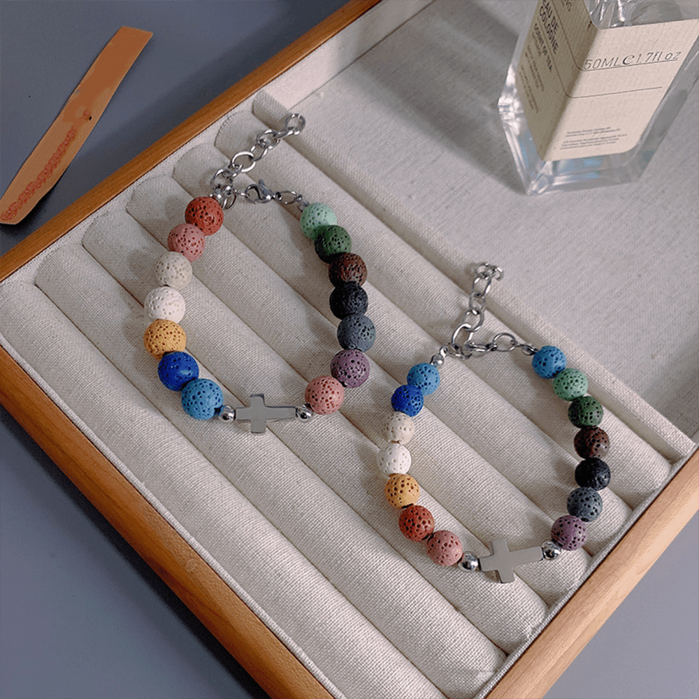 Bracelet croix minimaliste en perles de pierre volcanique colorée, signé Christianartworkshop - image 1