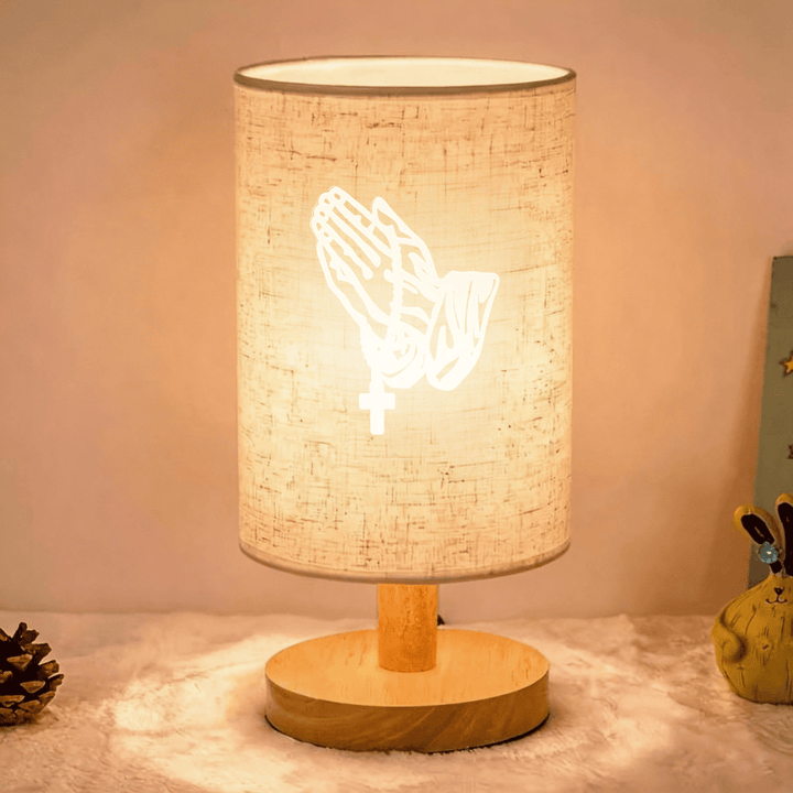 Christianartworkshop Lampe de table avec pied en bois naturel, abat-jour en tissu et motif de mains jointes en croix : un symbole de calme et de sérénité nocturne. - Croix - image 0